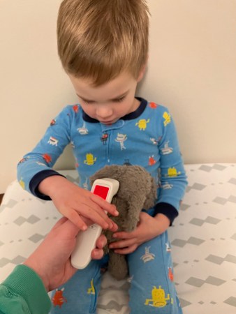 White male toddler takes his stuffed animal elephant's temperature